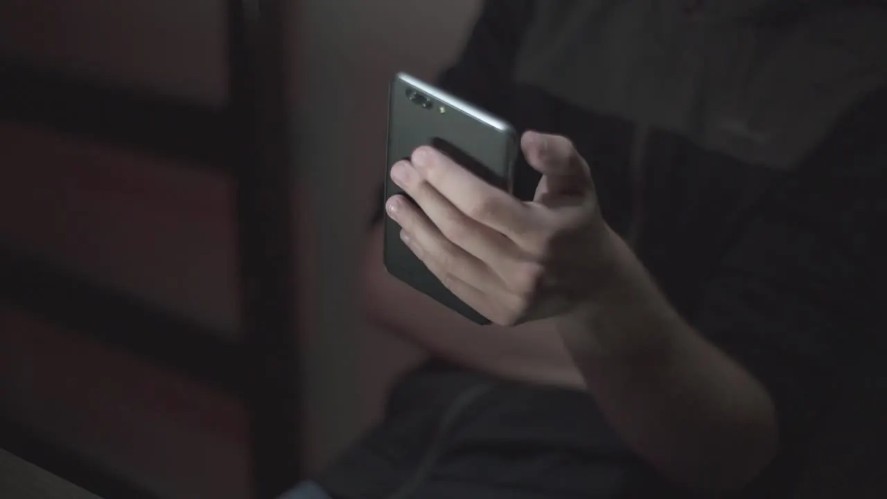 A person holding a smartphone in a dimly lit room