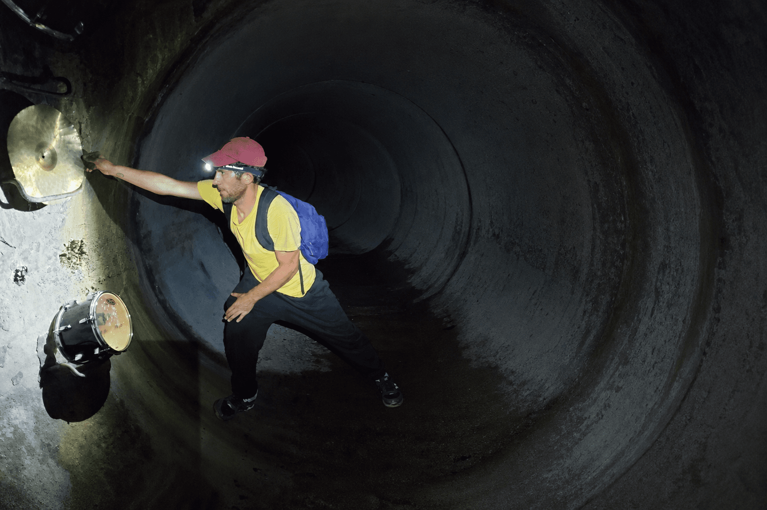 Robbie Hansen reaching toward a cymbal mounted inside a tunnel